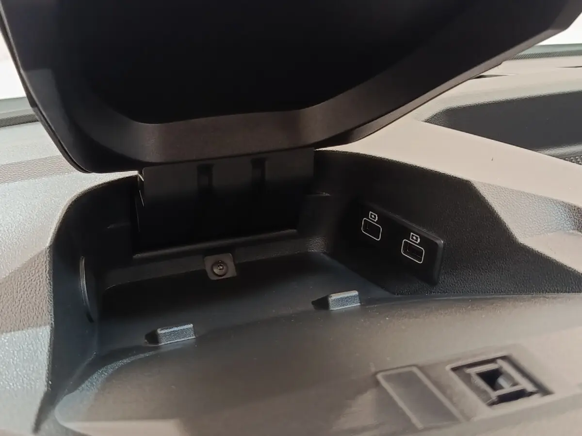 Gros plan sur le compartiment de rangement ouvert avec deux ports USB à l'avant du tableau de bord noir.
