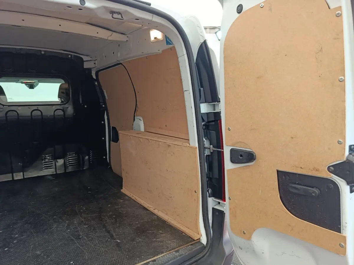 Vue intérieure arrière du Renault Express blanc 2023 avec cloison pleine et revêtement bois des parois de chargement.
