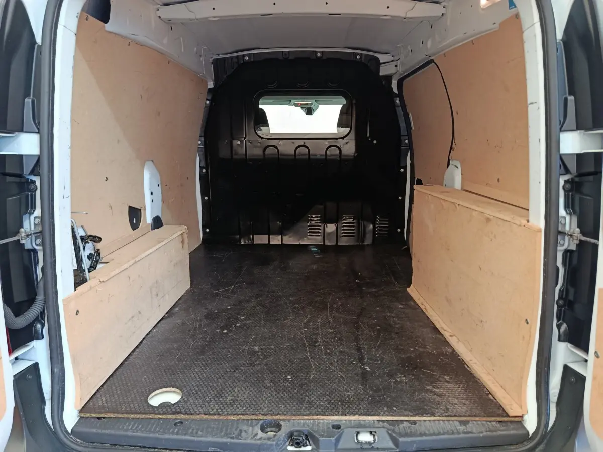 Vue intérieure arrière du Renault Express blanc 2023, montrant l'espace de chargement avec cloison pleine vitrée et revêtement bois.