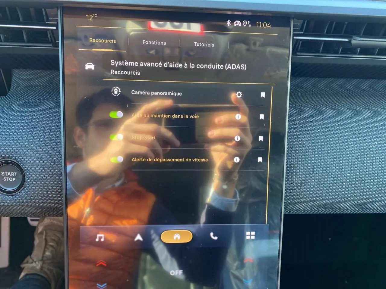 Écran tactile central du Citroën C5 Aircross 2026 affichant les aides à la conduite, avec reflet d'une personne en gilet orange.