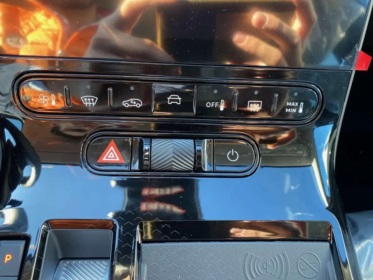 Gros plan sur la console centrale noire brillante du Citroën C5 Aircross hybride, avec commandes climatisation et bouton hazard.