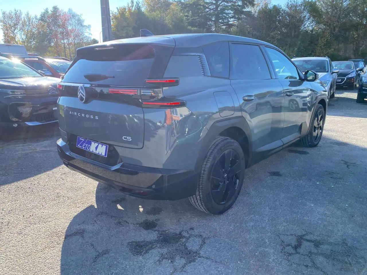 Vue 3/4 arrière droite d'un Citroën C5 Aircross vert métallisé avec jantes alliage noires sur parking en extérieur.