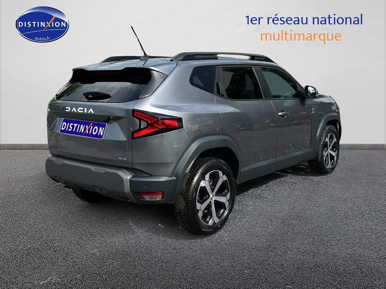 Vue 3/4 arrière droite du Dacia Duster gris schiste 2025 avec jantes alu et barres de toit visibles.
