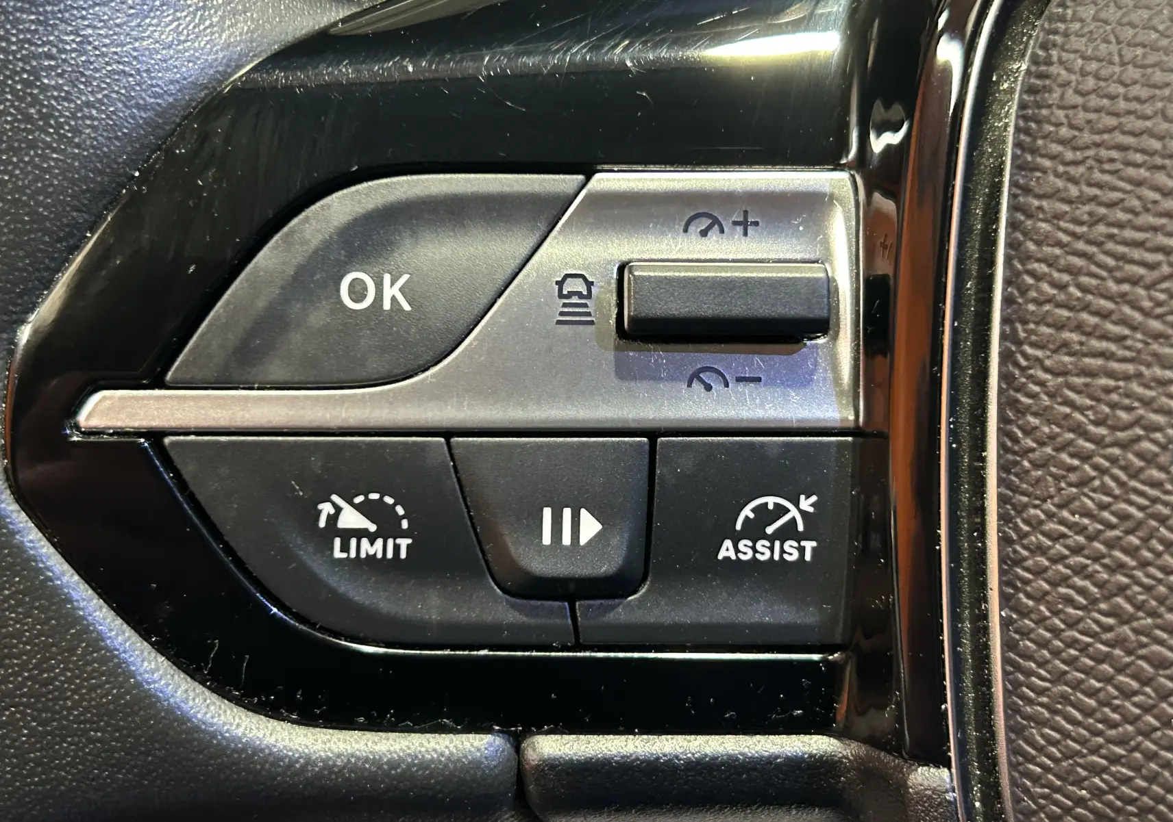 Gros plan sur les commandes au volant de la Peugeot 308 2024, boutons de limitation et assistance de vitesse visibles.