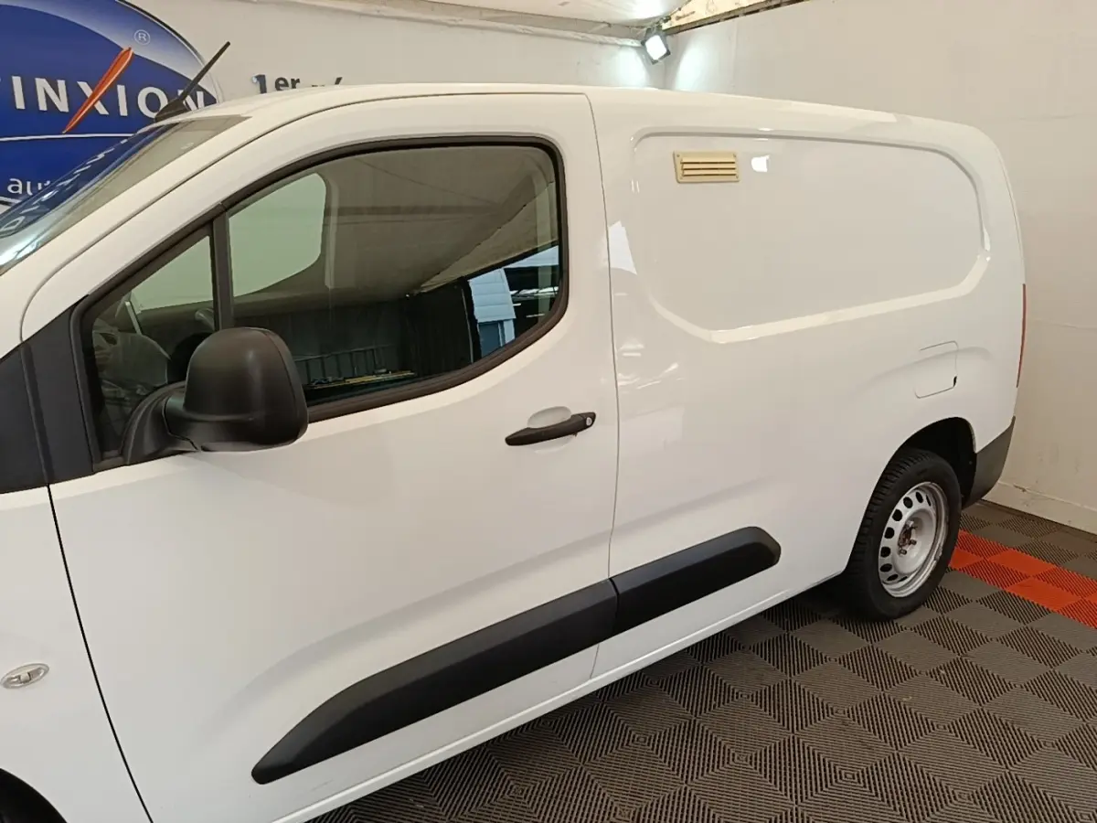 Vue de profil côté gauche d’un Citroën Berlingo XL blanc avec protections latérales noires et jante acier simple.