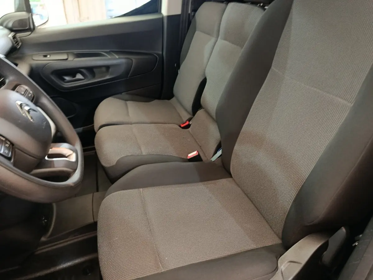 Vue intérieure côté conducteur du Citroën Berlingo 2020, sièges tissu gris et volant multifonctions noir.