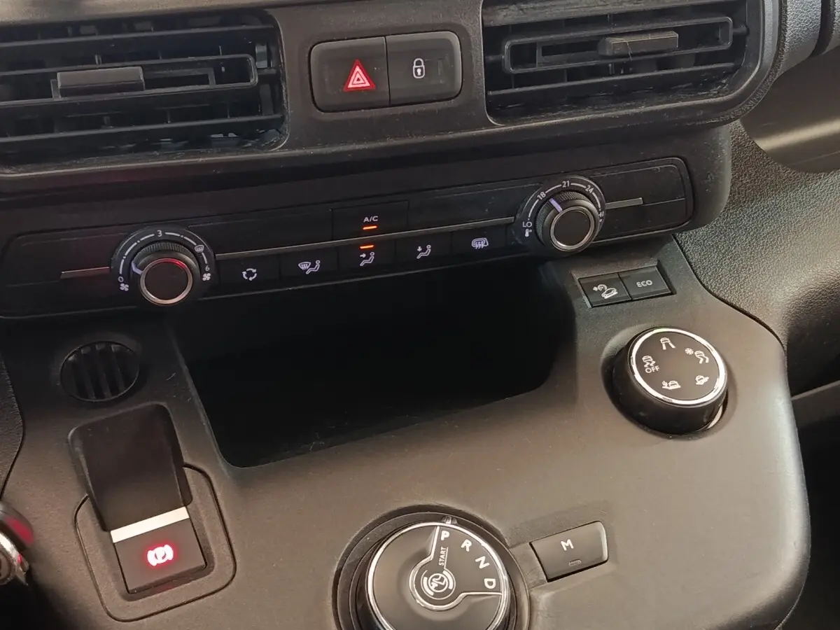 Vue rapprochée du tableau de bord et console centrale noire du Citroën Berlingo blanc, avec commandes climatisation et boîte auto.