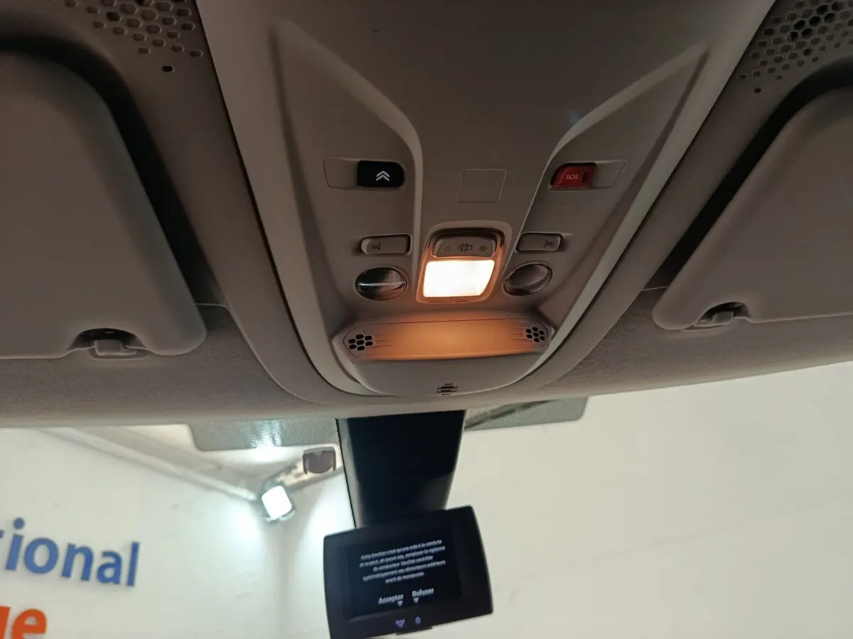 Vue intérieure du plafonnier allumé avec commandes et écran tactile du Citroën Berlingo blanc 2020.