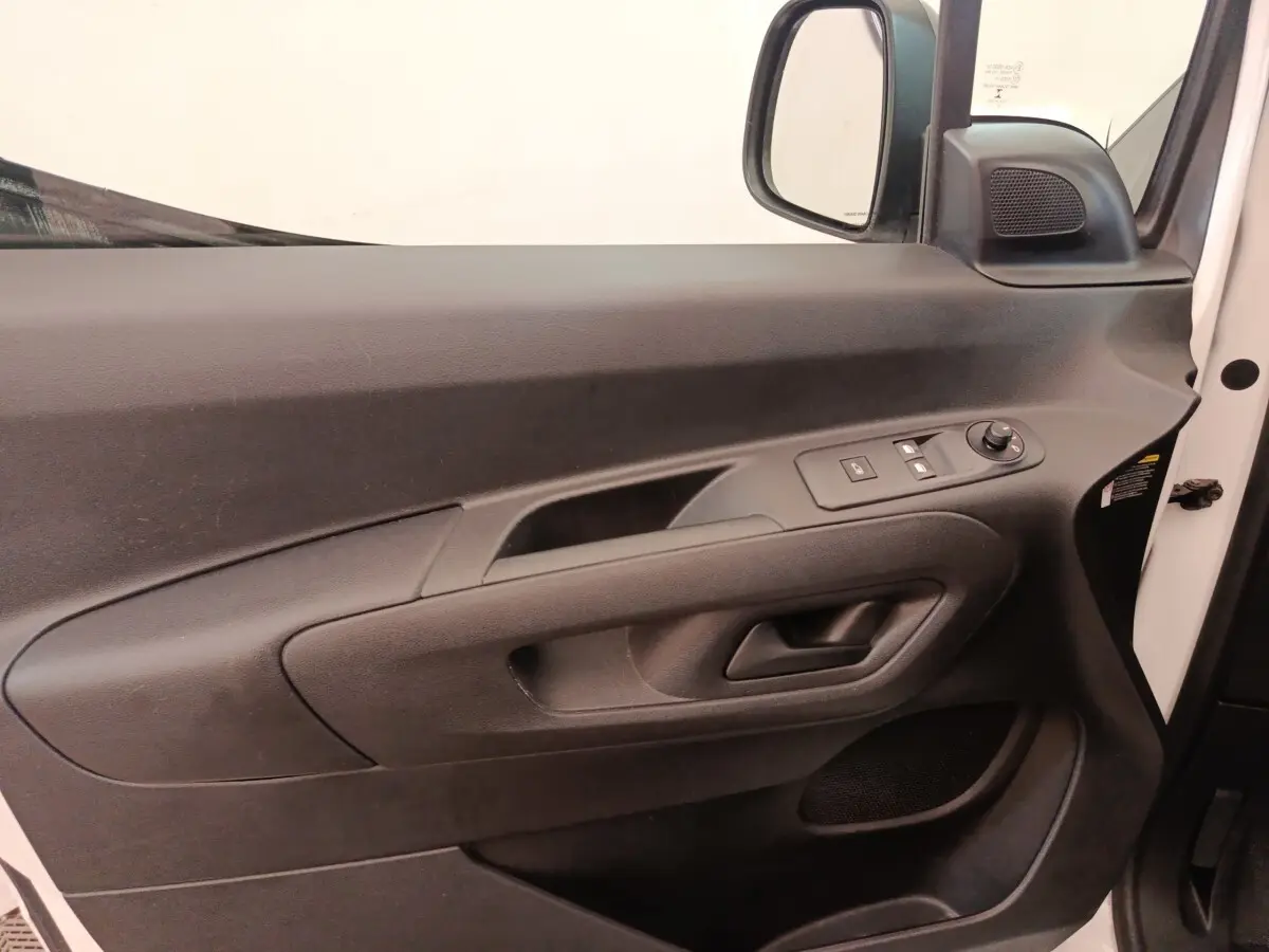 Vue intérieure côté conducteur de la porte noire du Citroën Berlingo blanc avec commandes électriques des vitres et rétroviseur.