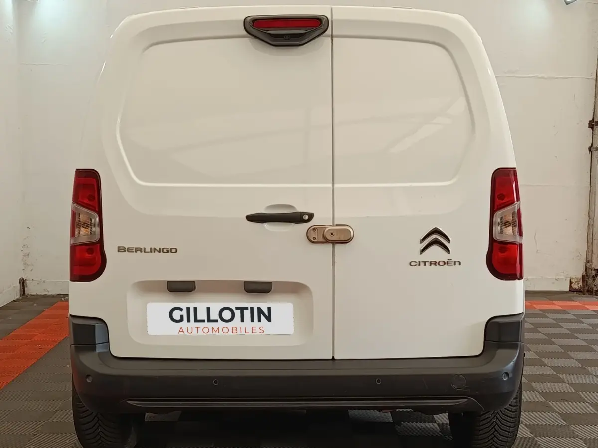 Vue arrière d’un Citroën Berlingo blanc de 2020 avec portes battantes et logo visible sur fond d’atelier.