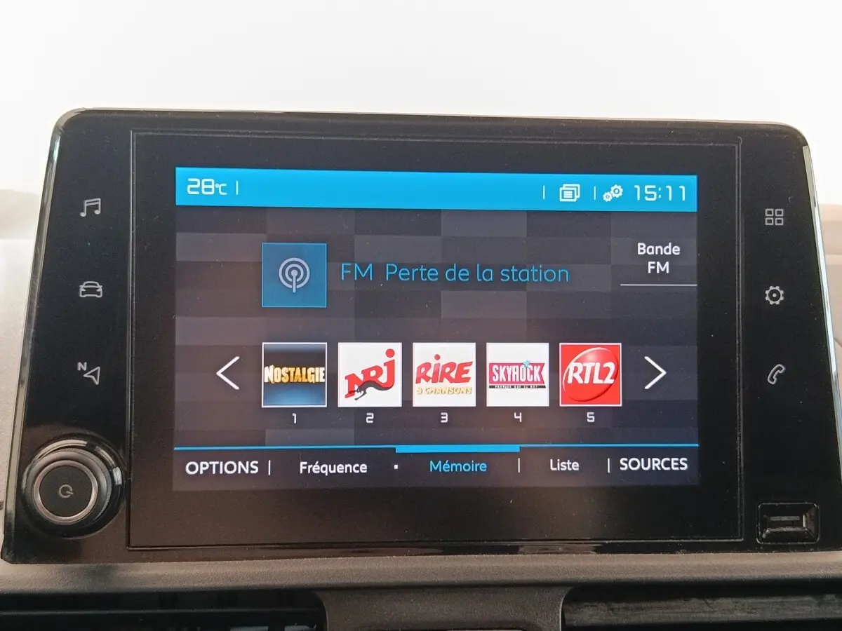 Écran tactile central du tableau de bord du Citroën Berlingo blanc, affichant les stations radio FM.