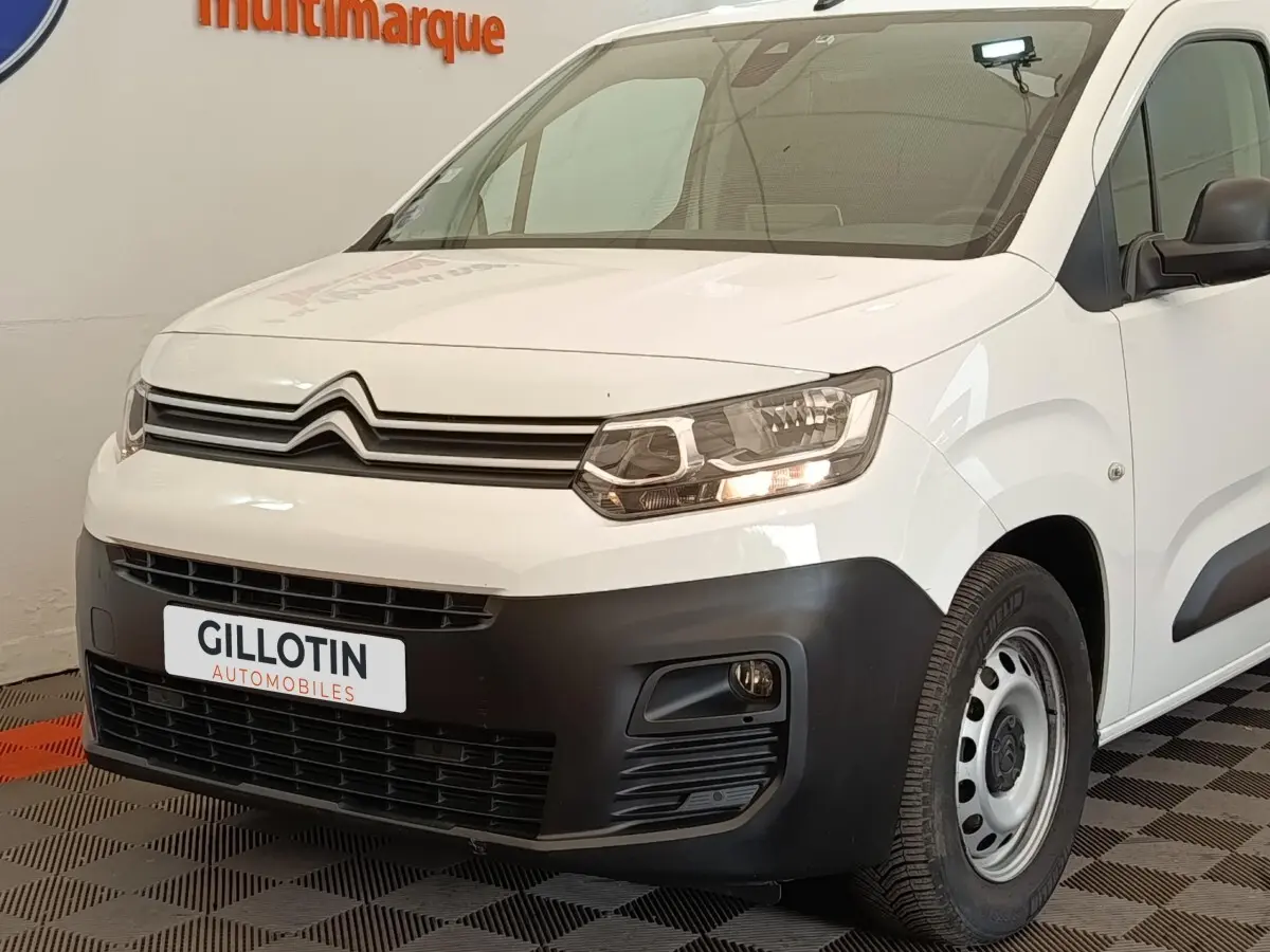 Vue 3/4 avant droit d'un Citroën Berlingo blanc avec pare-chocs noir et jante acier simple.