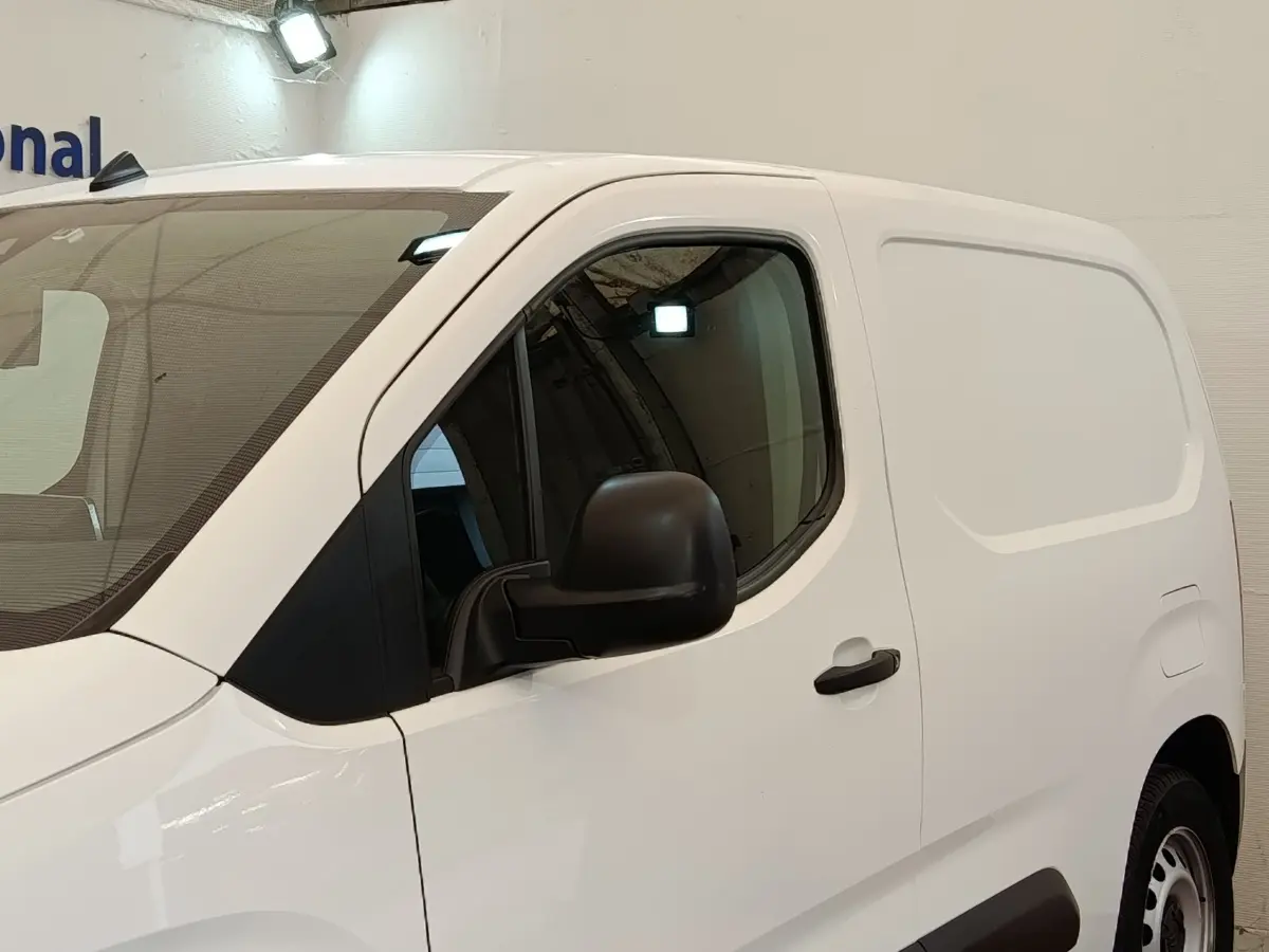 Vue de profil côté gauche d’un utilitaire Citroën Berlingo blanc avec porte latérale pleine et rétroviseur noir.