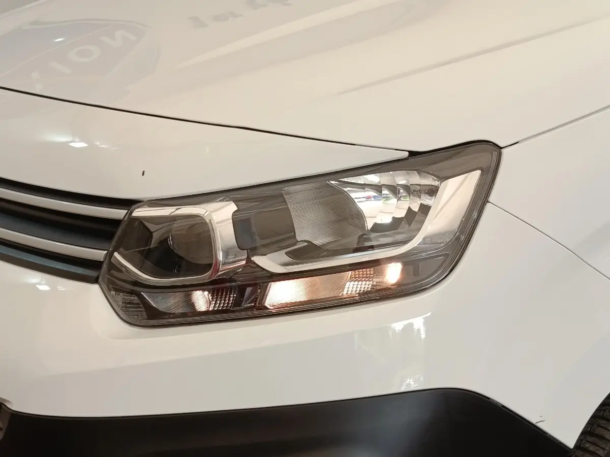 Gros plan sur le phare avant droit du Citroën Berlingo blanc, avec calandre et partie de la carrosserie visibles.