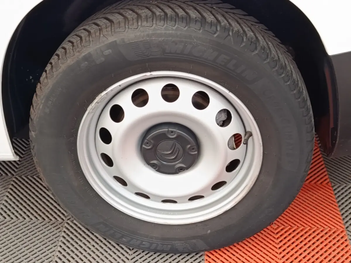 Gros plan sur la roue avant droite d’un Citroën Berlingo blanc avec jante acier et pneu Michelin.