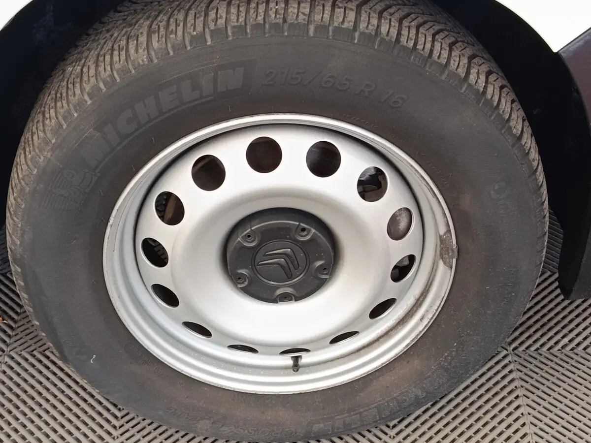 Gros plan sur la roue acier blanche avec logo Citroën, pneu Michelin, sur un Citroën Berlingo blanc.