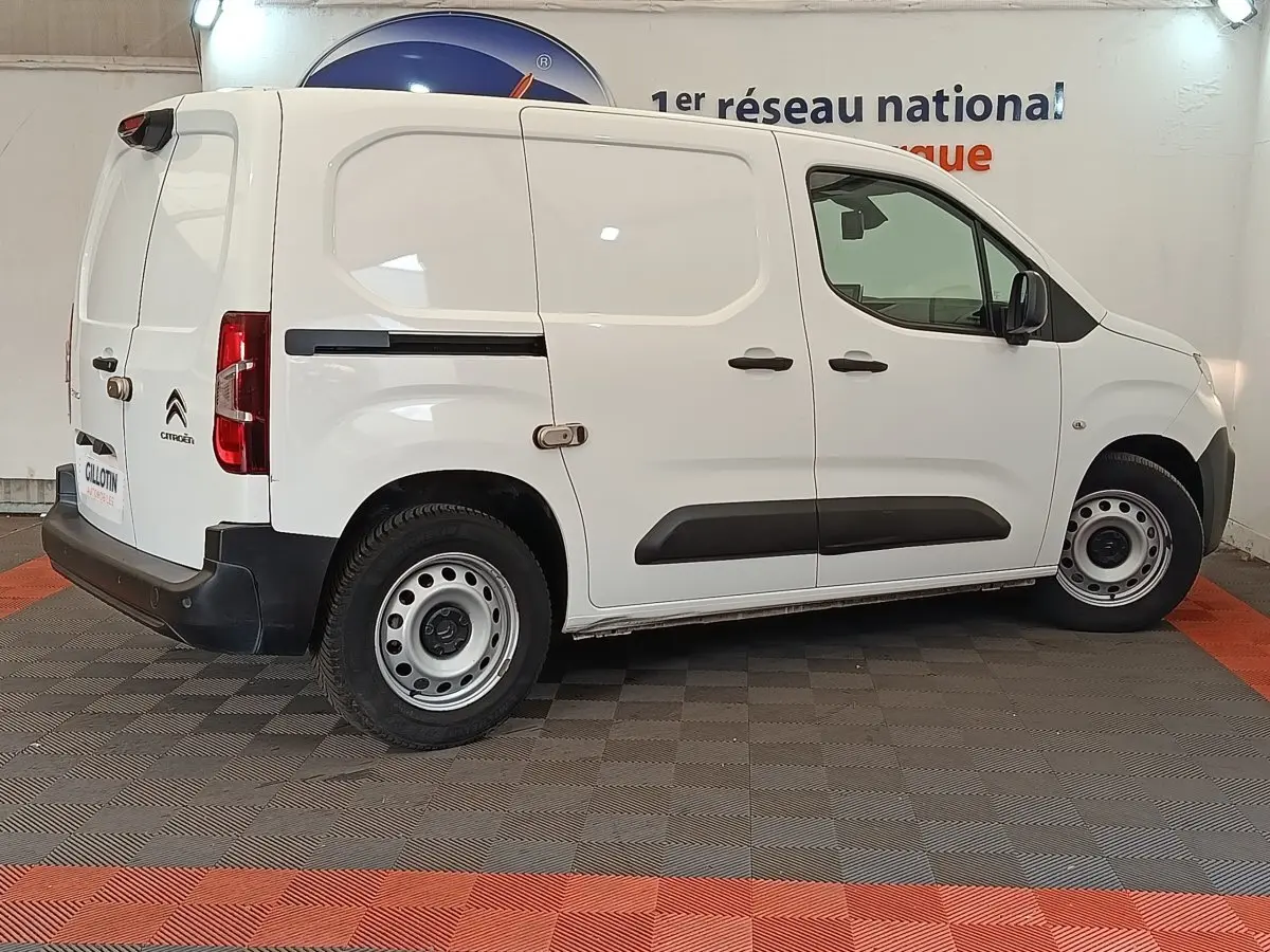 Vue de profil droit d’un utilitaire Citroën Berlingo blanc avec jantes acier et protections latérales noires.