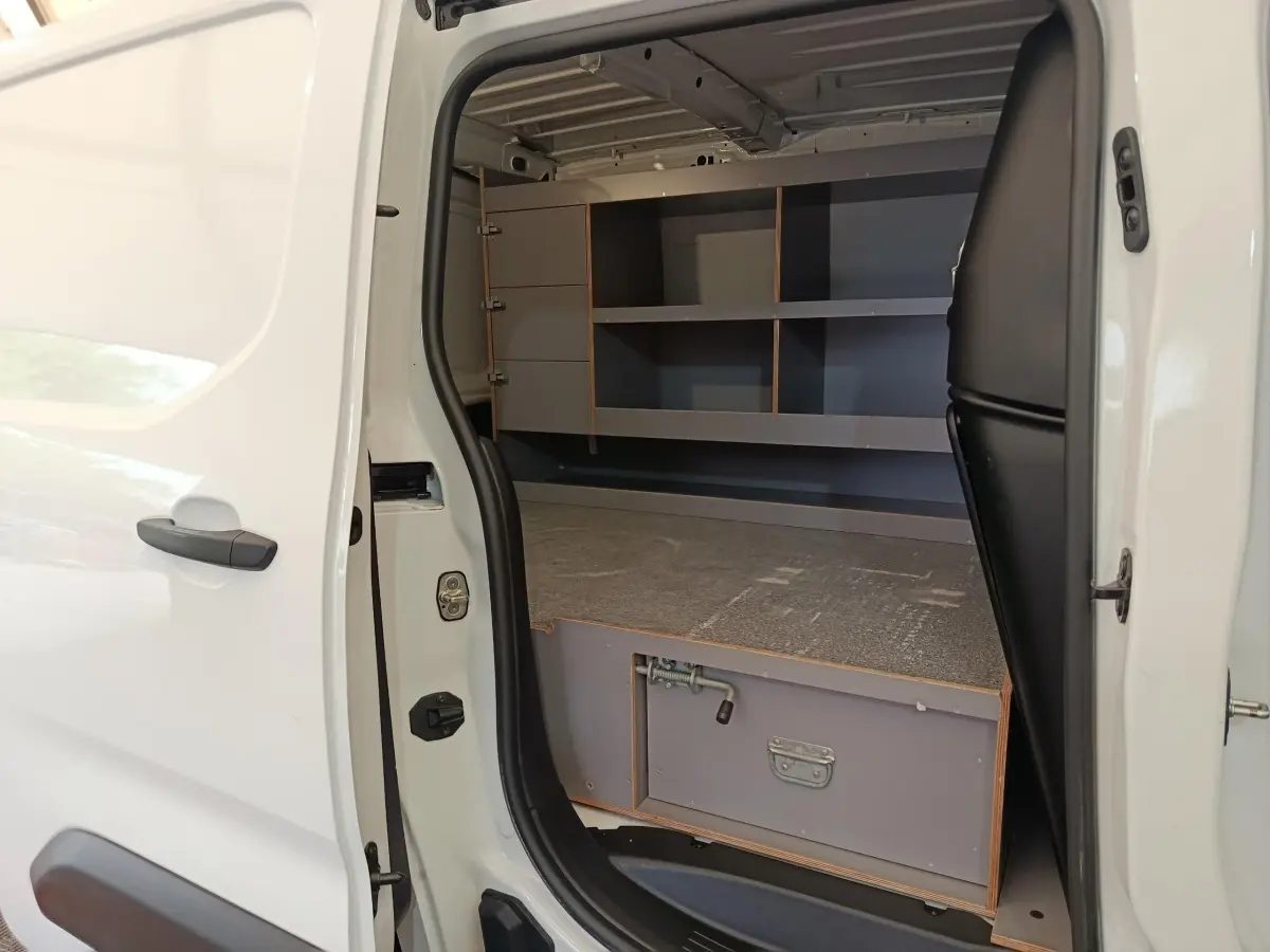 Vue latérale gauche du Citroën Berlingo blanc 2020 avec porte coulissante ouverte montrant l'aménagement intérieur de rangement.