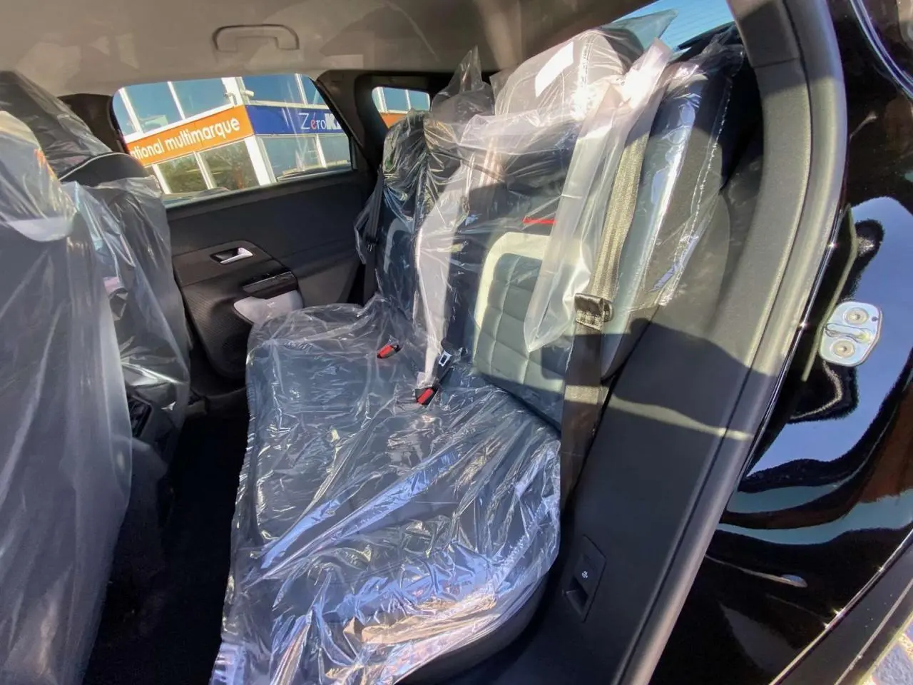 Vue intérieure côté gauche des sièges arrière protégés par des housses plastiques d'un Citroën C5 Aircross noir.