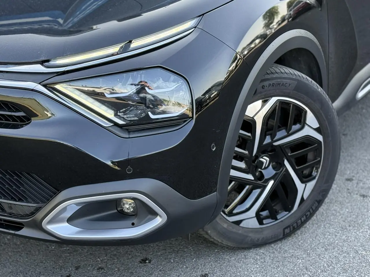 Gros plan sur l'avant droit noir Perla du Citroën C4 X 2024, mettant en valeur le phare LED et la jante alliage 18'' Aeroblade.