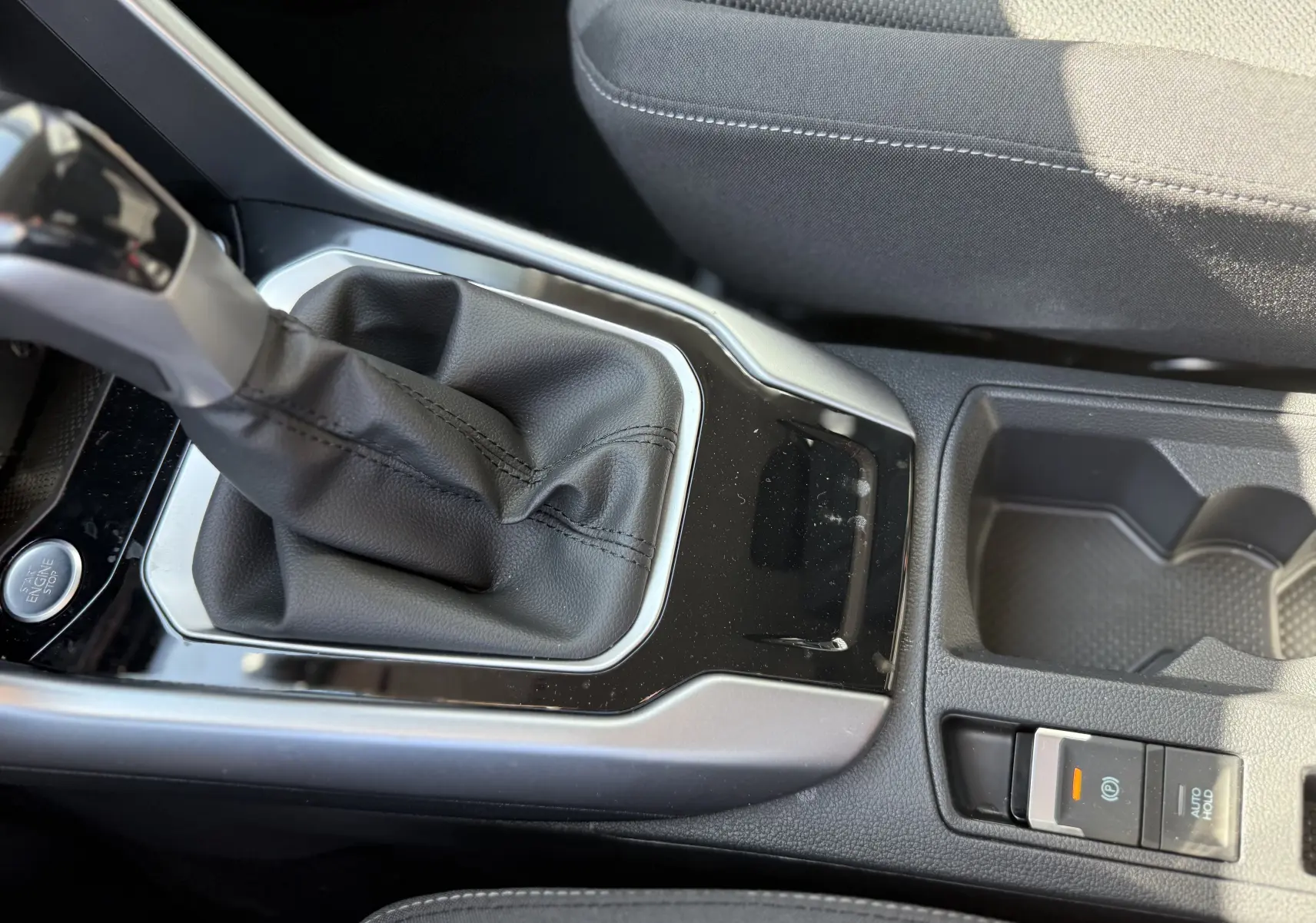 Gros plan sur la console centrale du Volkswagen T-Roc gris pyrite 2025, montrant le levier de vitesse automatique et le frein à main électronique.