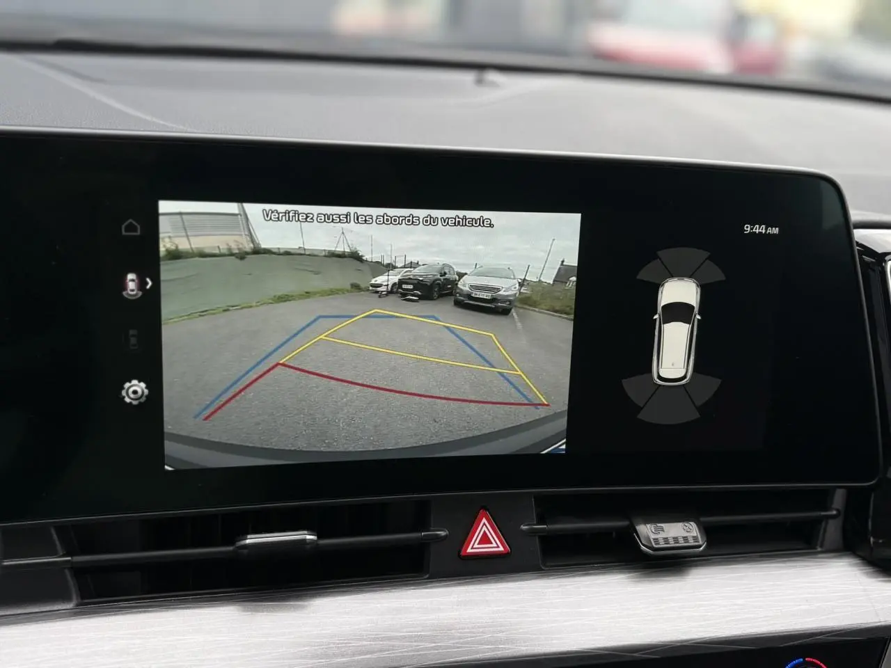 Écran tactile 12" montrant la caméra de recul du Kia Sportage gris perle avec lignes de guidage colorées.