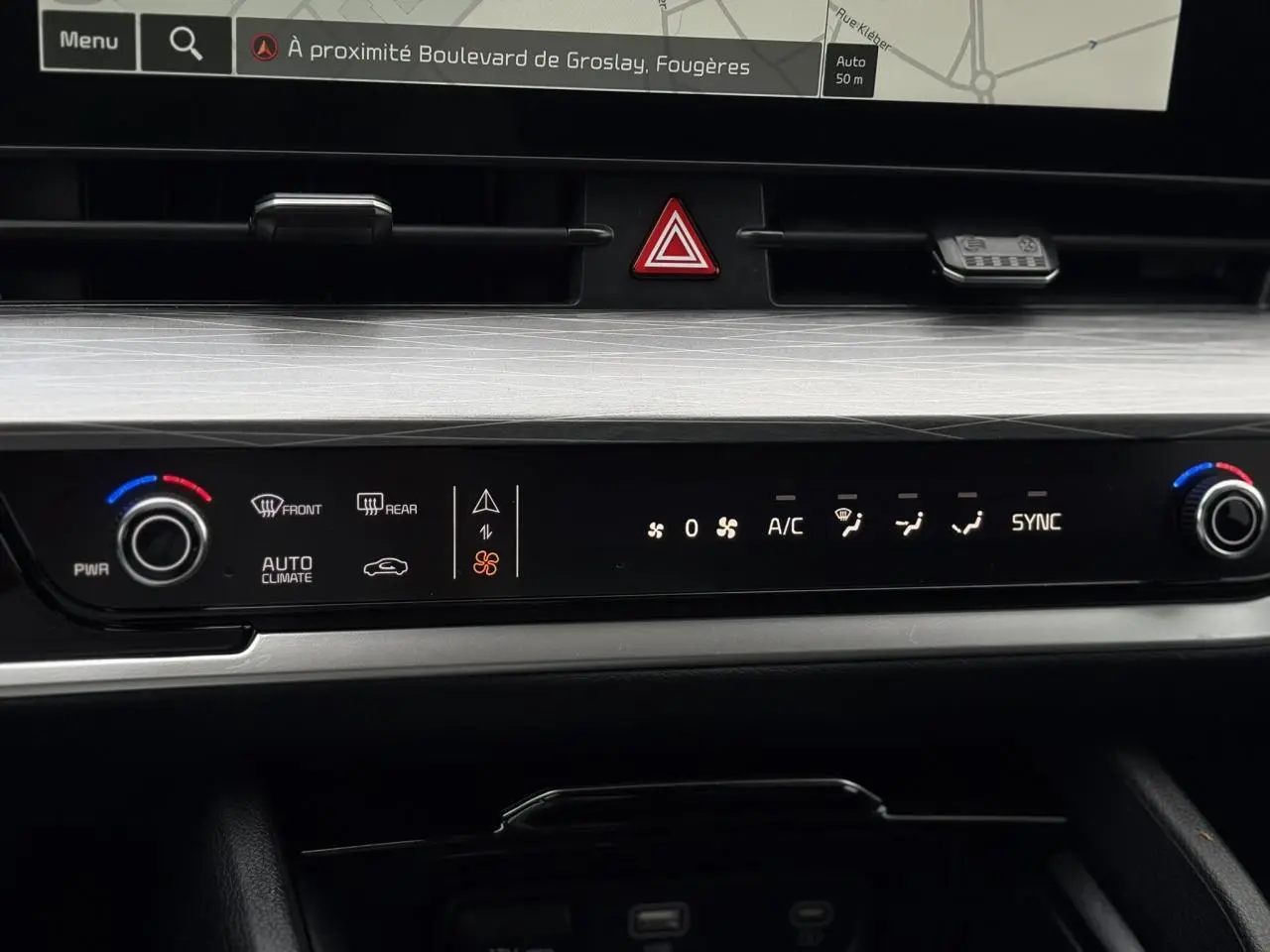 Plan rapproché du tableau de bord noir et gris du KIA SPORTAGE 2025 montrant l'écran tactile 12" et les commandes de climatisation digitales.