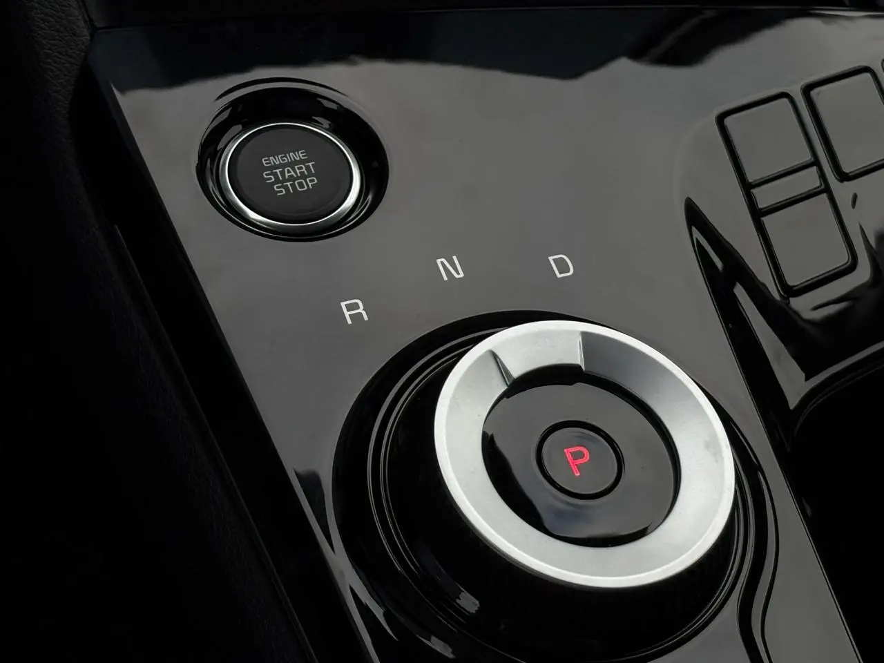 Gros plan sur la molette de sélection de la boîte auto et bouton start/stop du Kia Sportage gris perle.