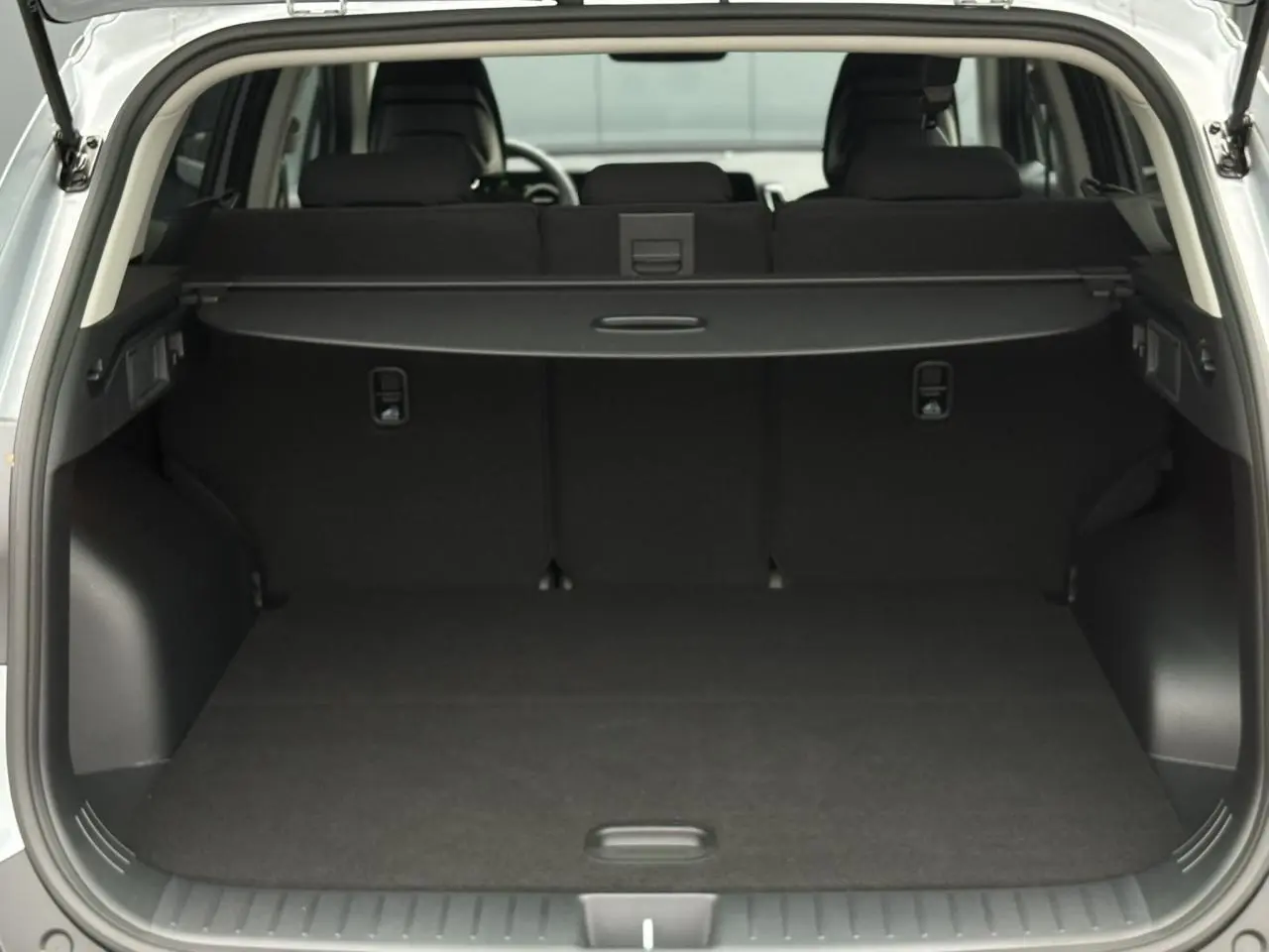 Coffre ouvert vu de l'arrière d'un KIA SPORTAGE gris perle, montrant l'espace de chargement et la plage arrière.