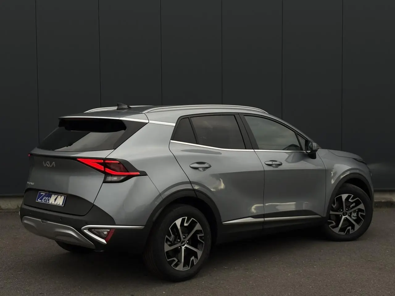 KIA SPORTAGE gris perle vu en 3/4 arrière droit, avec jantes alliage 18 pouces et feux arrière LED distinctifs.