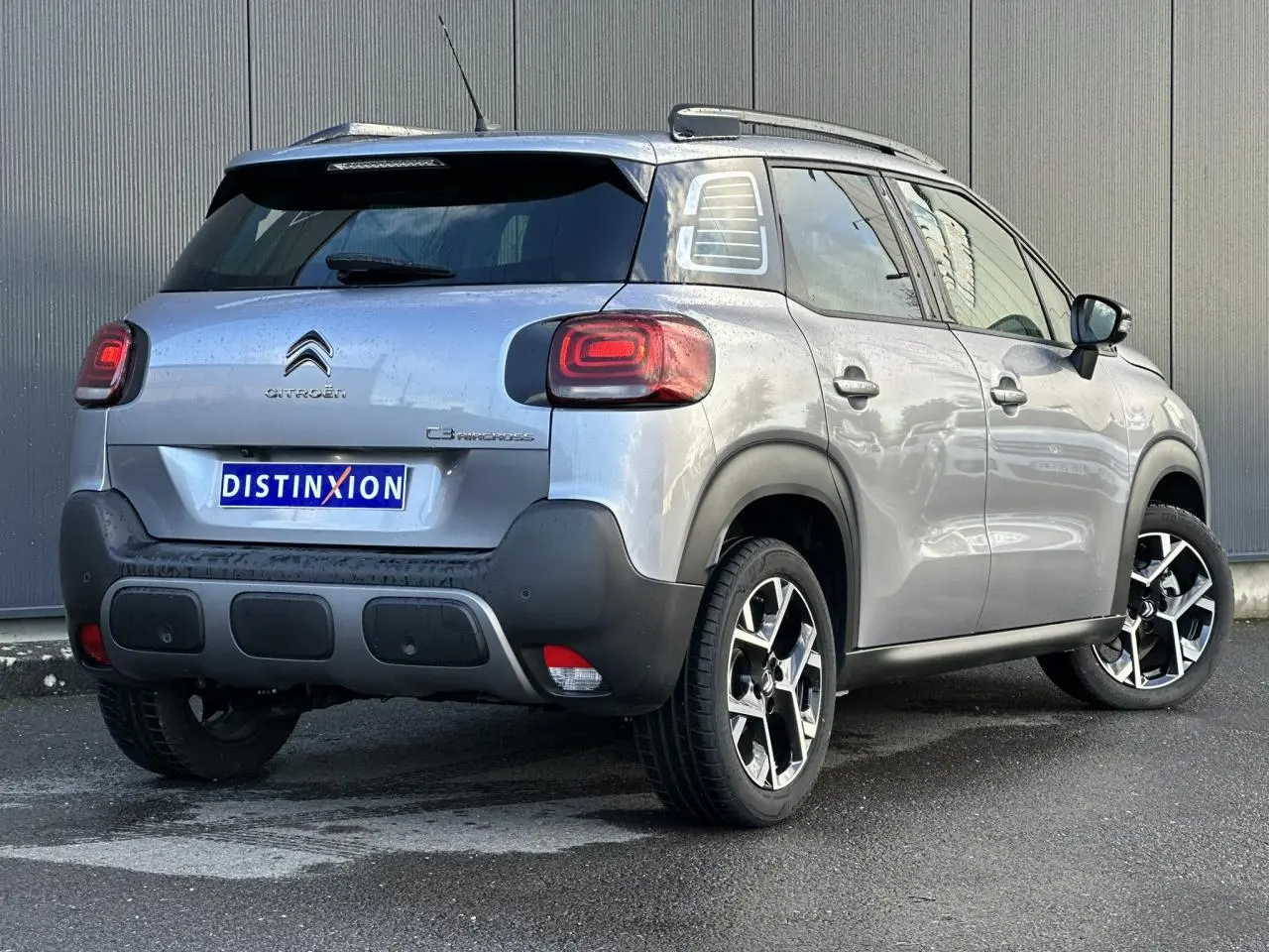 Citroën C3 Aircross gris Artense vue 3/4 arrière droit avec jantes alliage et barres de toit noires.