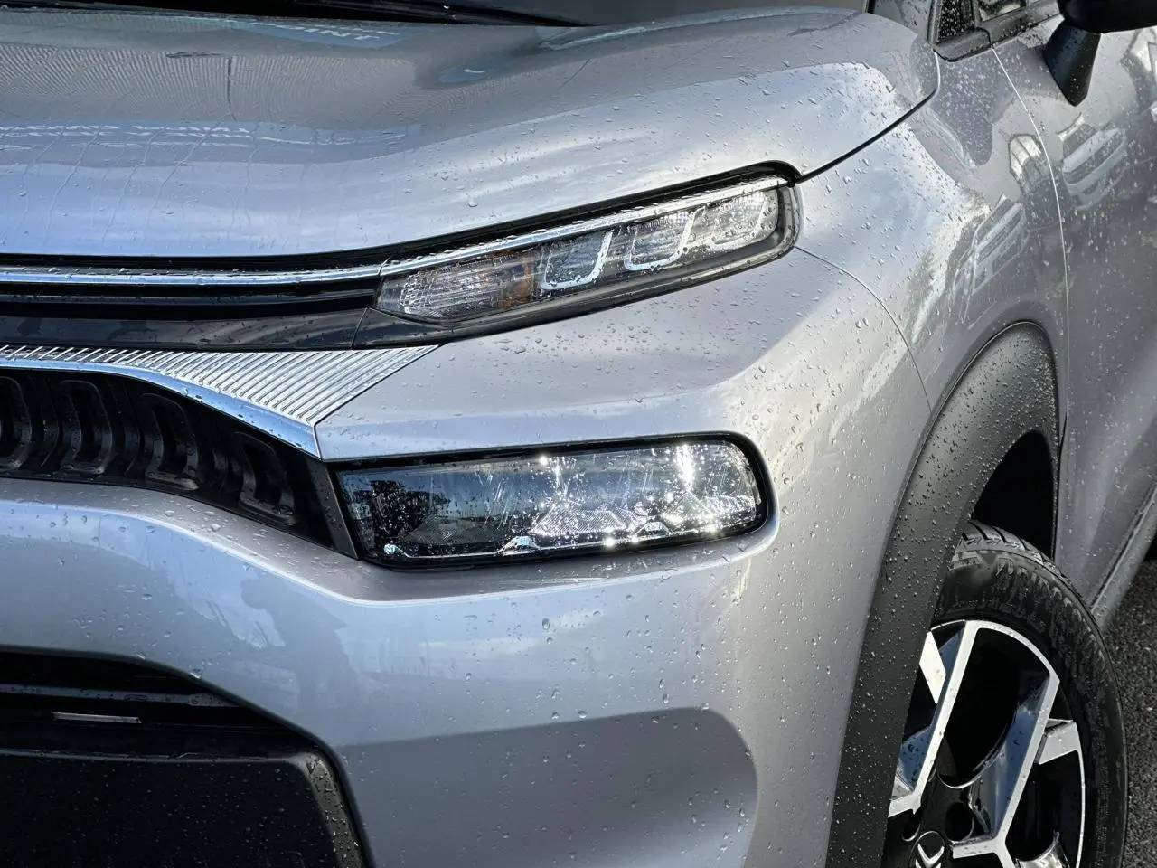 Gros plan sur l'avant droit gris Artense du Citroën C3 Aircross 2024 avec phares LED et jante alliage diamantée.
