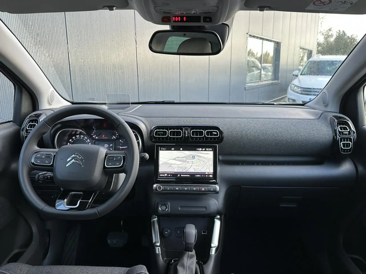 Vue intérieure frontale du tableau de bord et volant noir du Citroën C3 Aircross 2024 avec écran tactile GPS allumé.