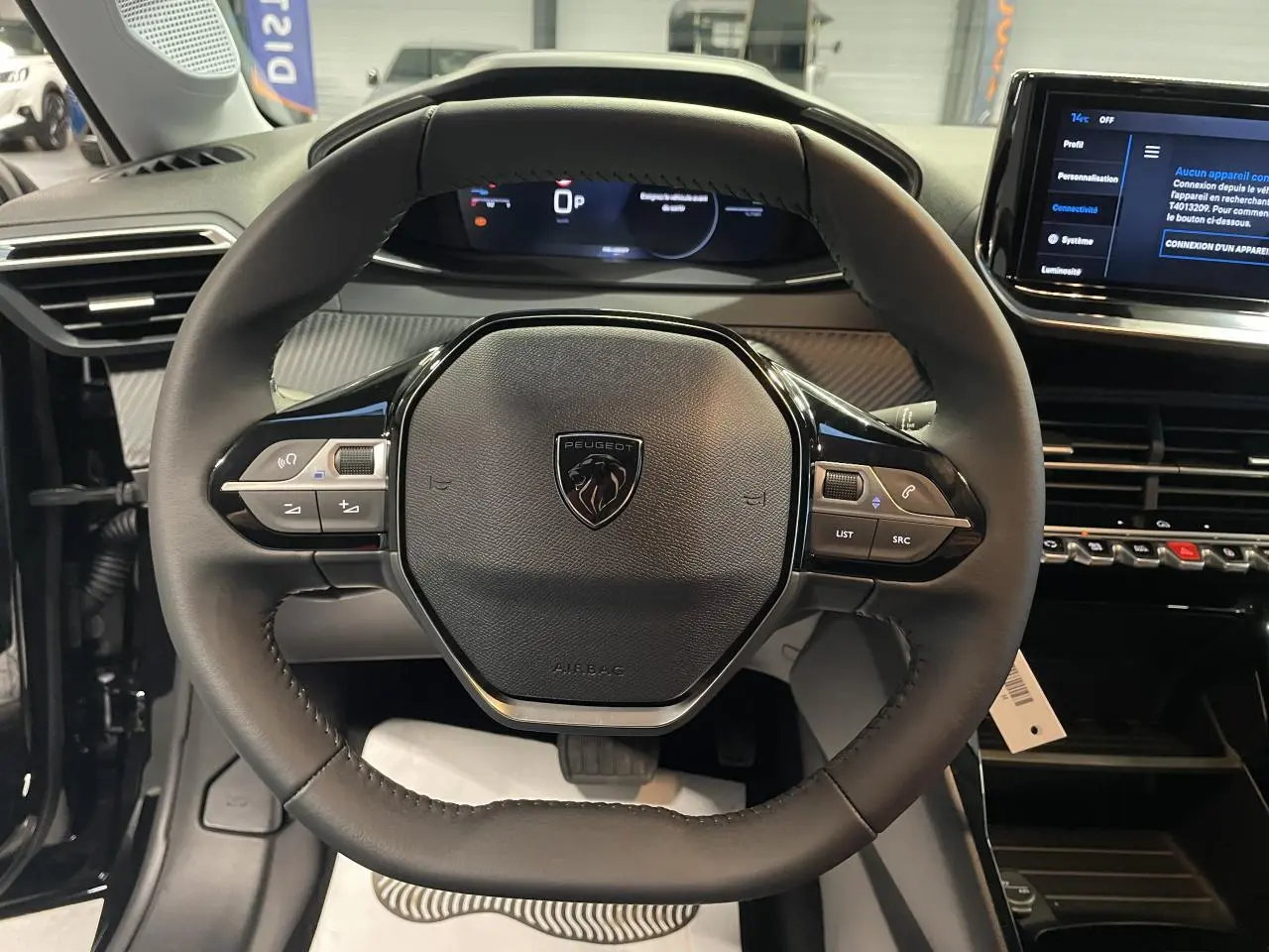 Vue rapprochée du volant cuir noir du Peugeot 208 2025 avec commandes intégrées et tableau de bord numérique.