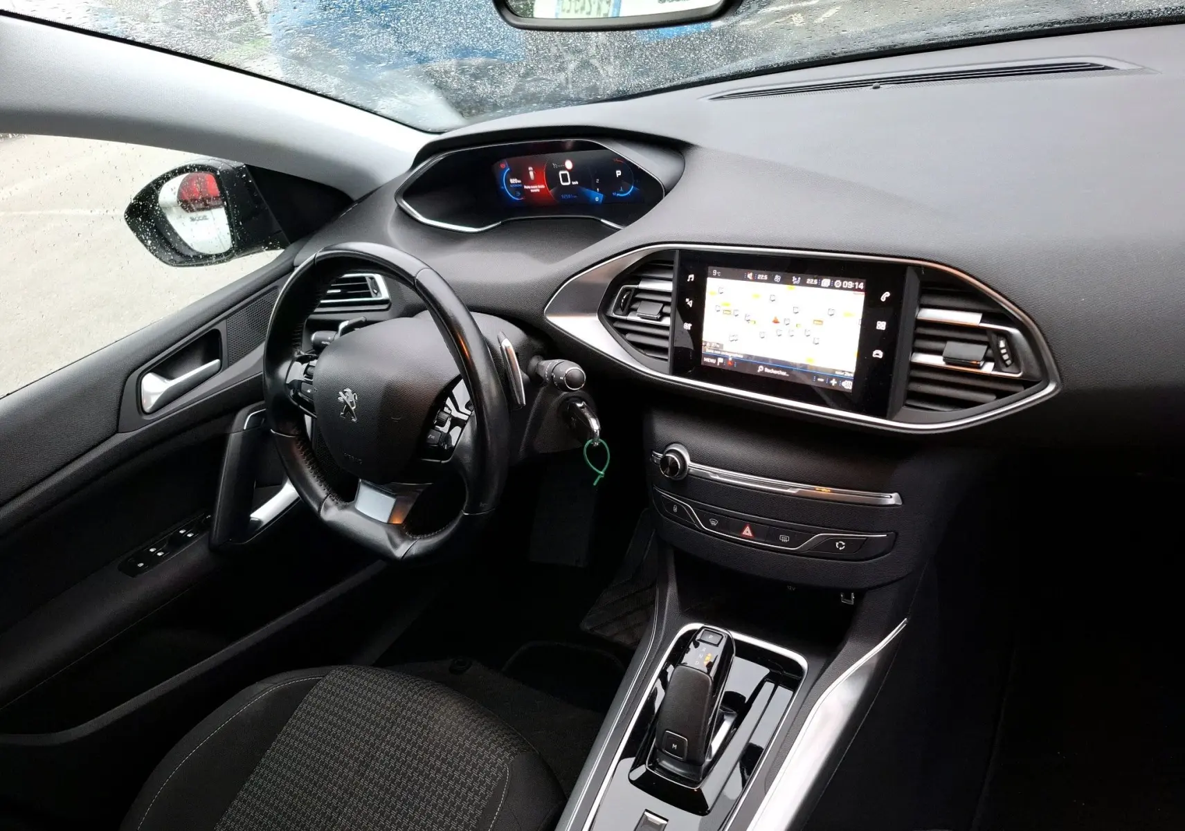 Vue intérieure côté gauche du tableau de bord noir de la Peugeot 308 SW avec écran tactile et volant multifonction.