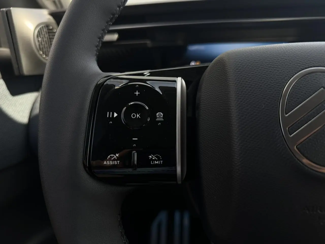 Gros plan sur la commande multifonction gauche du volant noir du Citroën C5 Aircross 2026, avec logo central visible.