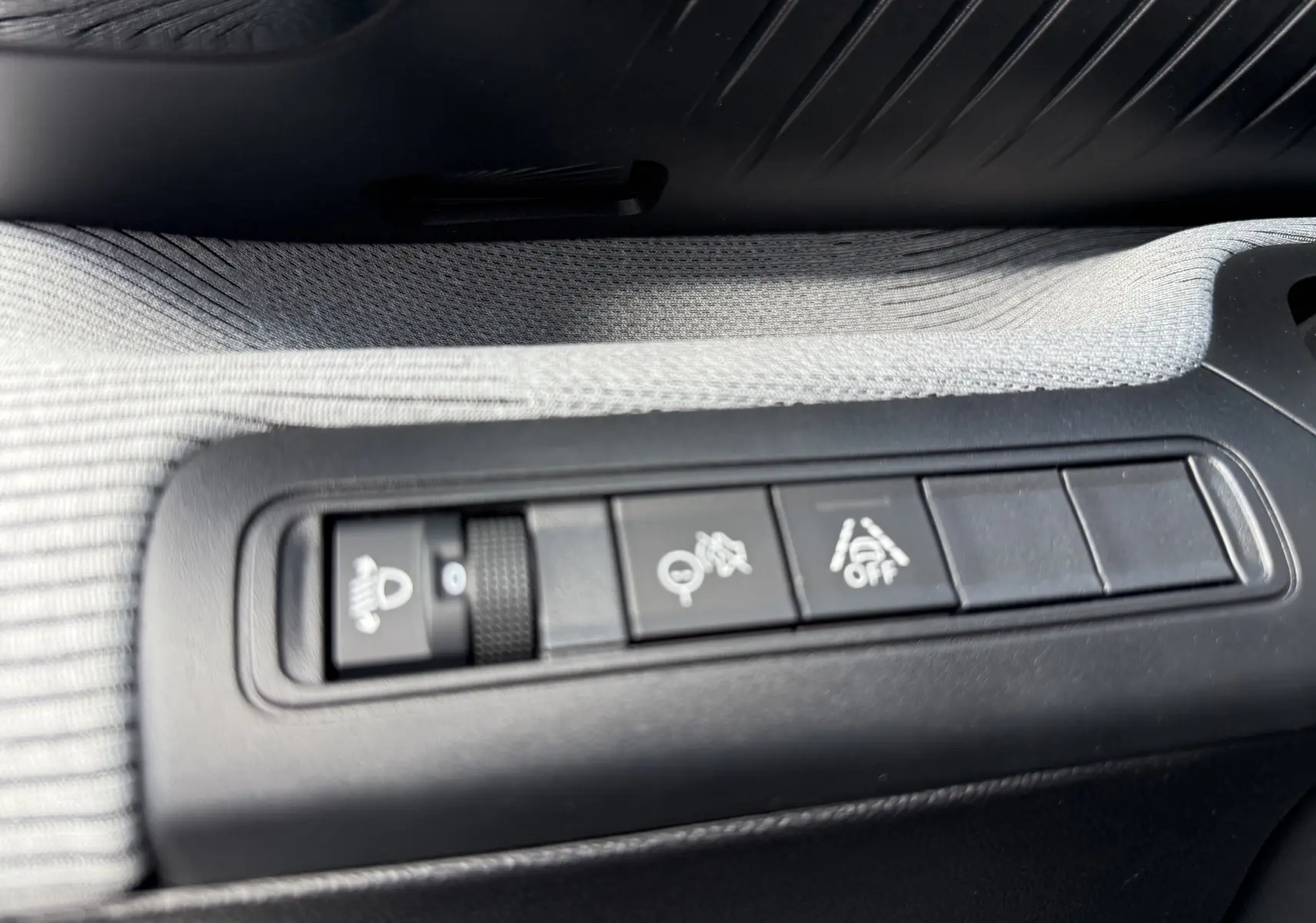 Gros plan sur les commandes noires intégrées dans un habillage tissu gris clair à l'intérieur de la Citroën C3 Aircross blanc banquise.