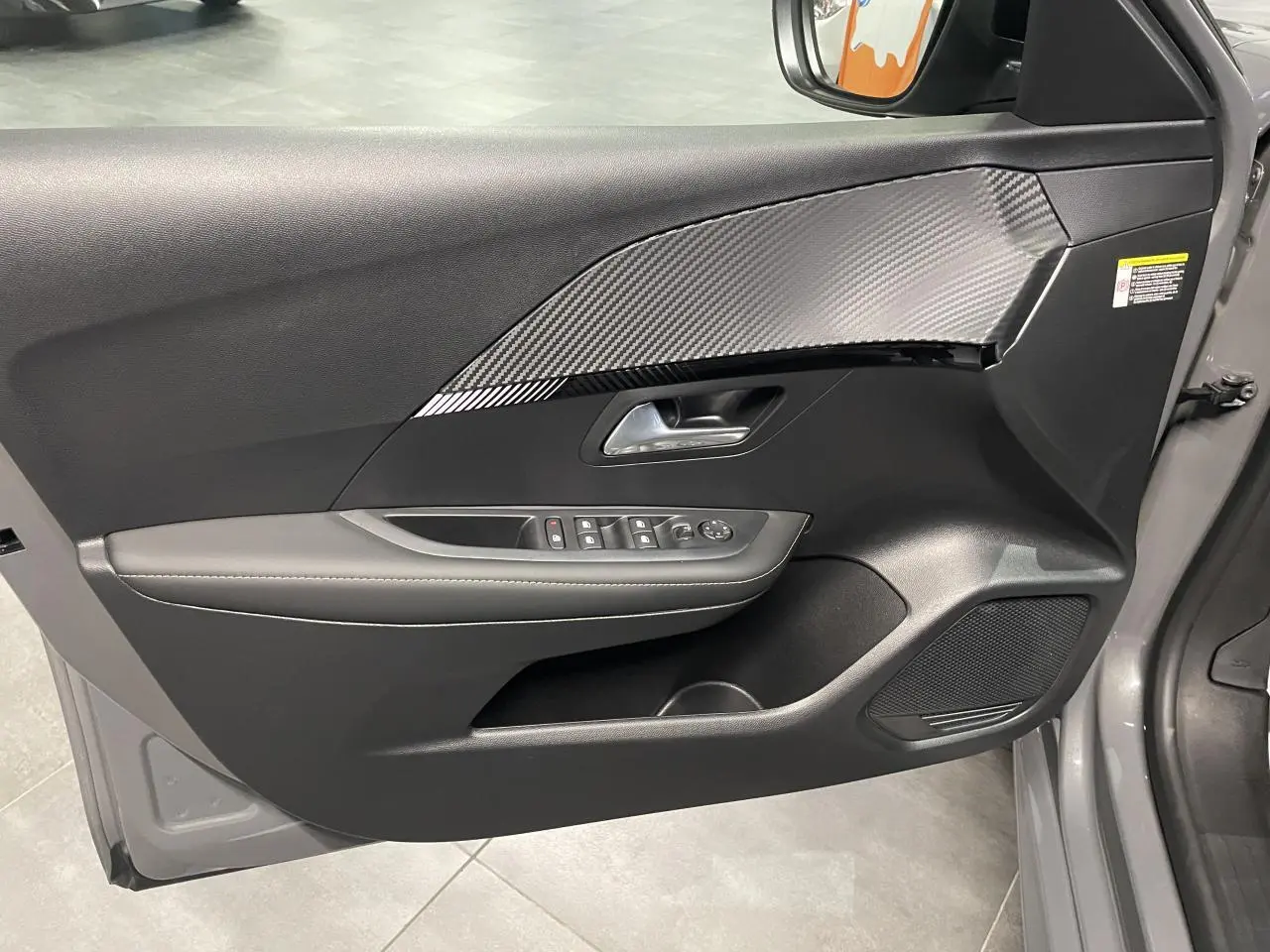 Vue intérieure côté gauche de la porte avant gris selenium avec insert carbone et commandes électriques.