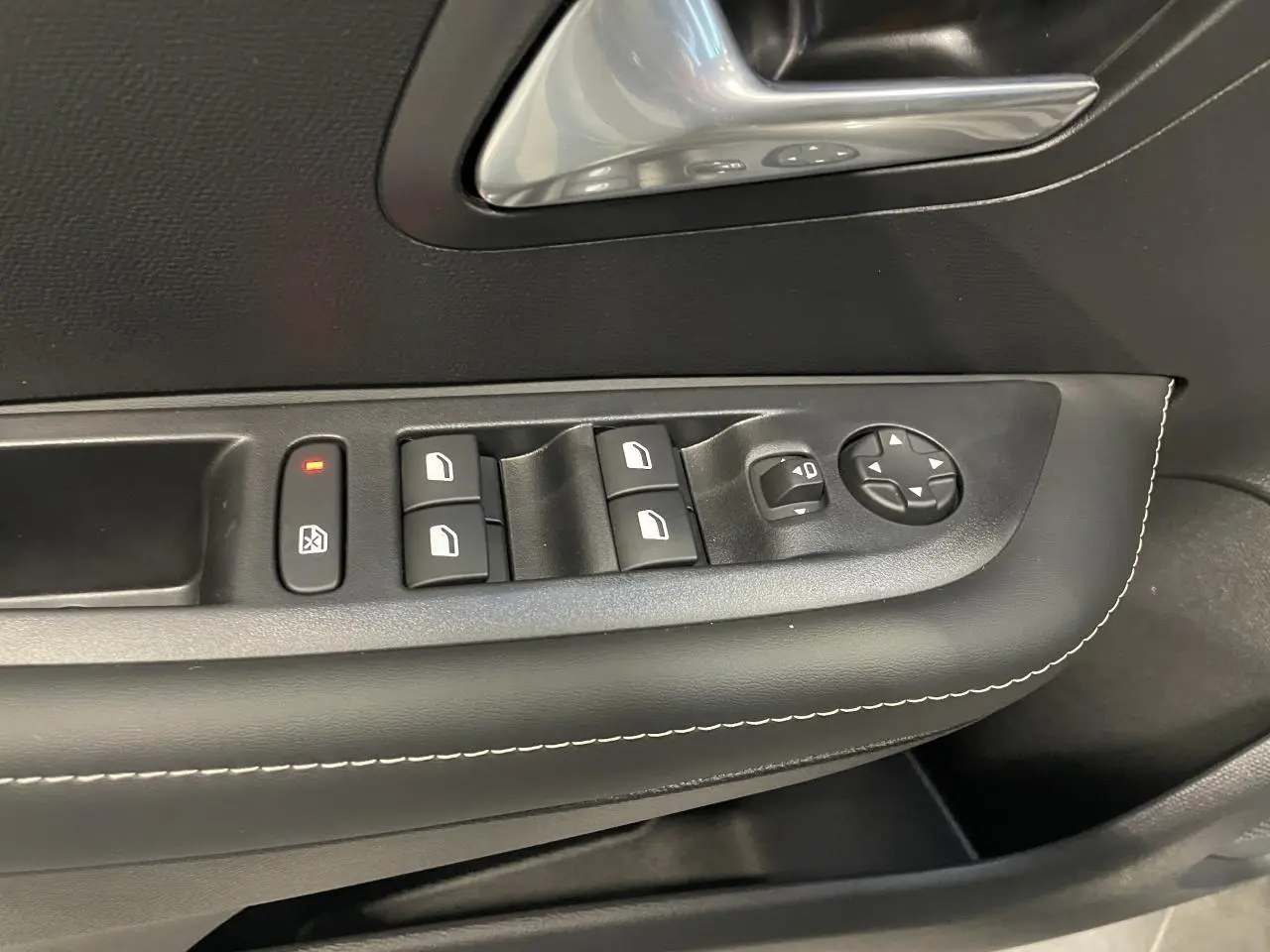 Détail des commandes de lève-vitres et réglage des rétroviseurs sur la porte avant gauche d’une Peugeot 208 gris Selenium.
