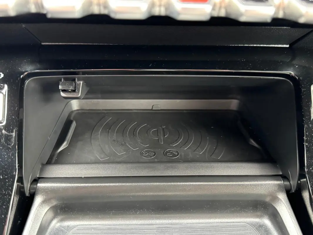 Gros plan sur le compartiment de recharge sans fil noir du Peugeot 208 Hybrid 110 e-DCS6 GT gris, intérieur moderne.