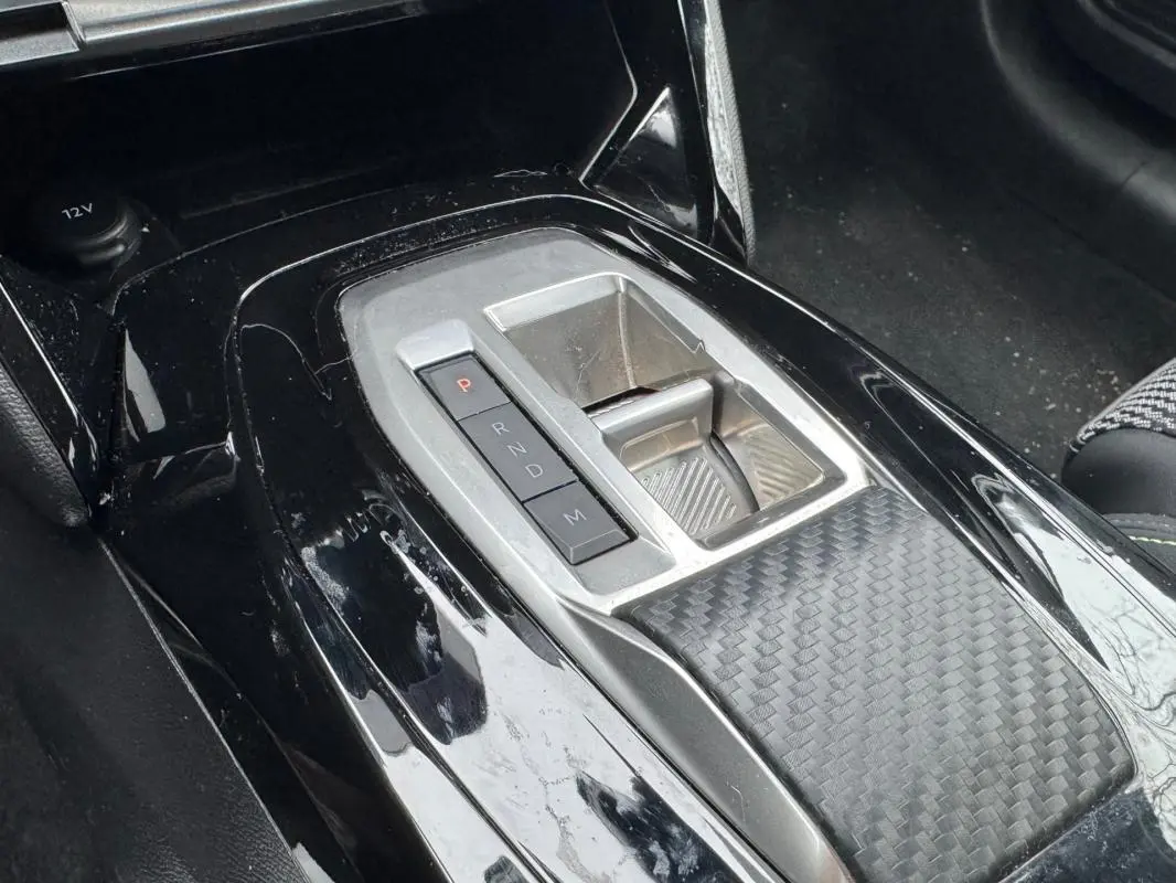 Gros plan sur la console centrale noire brillante de la Peugeot 208 Hybrid 110 e-DCS6 GT avec levier de vitesses automatique.
