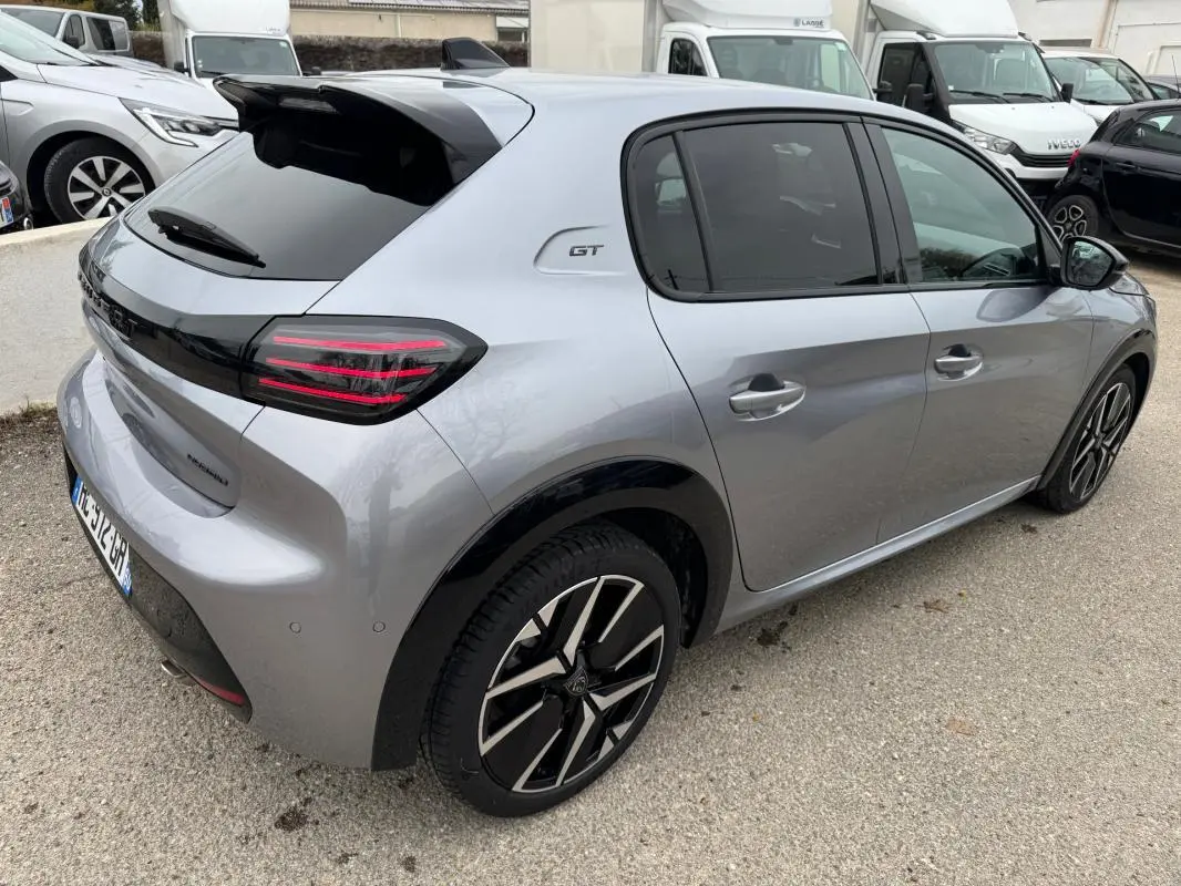 Vue 3/4 arrière droite d'une Peugeot 208 Hybrid 110 GT gris métallisé avec jantes alliage 17 pouces et toit noir.