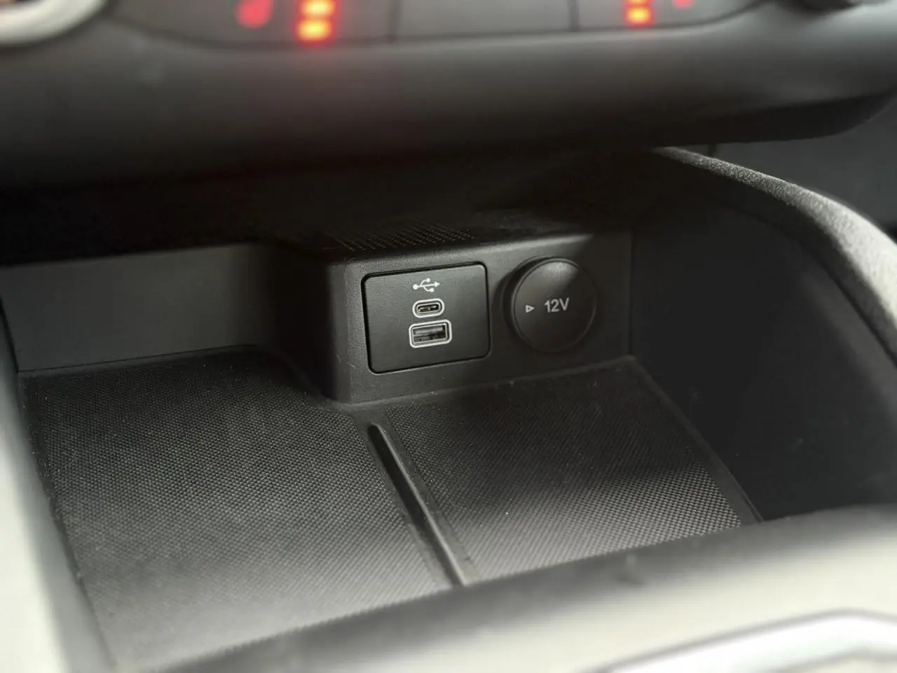 Gros plan sur la console centrale du Ford Kuga 2024 noir Obsidien, montrant les ports USB et prise 12V.