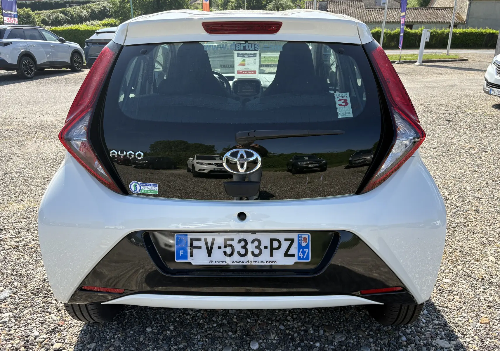 Vue arrière d'une Toyota Aygo MC blanche 2020 avec feux arrière en forme de flèche et plaque d'immatriculation française.