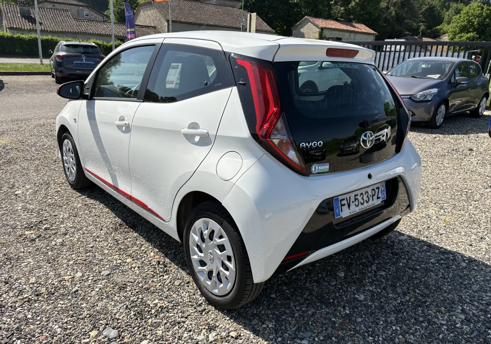Vue 3/4 arrière droite d'une Toyota Aygo MC blanche 2020 avec détails noirs et feux arrière rouges distinctifs.