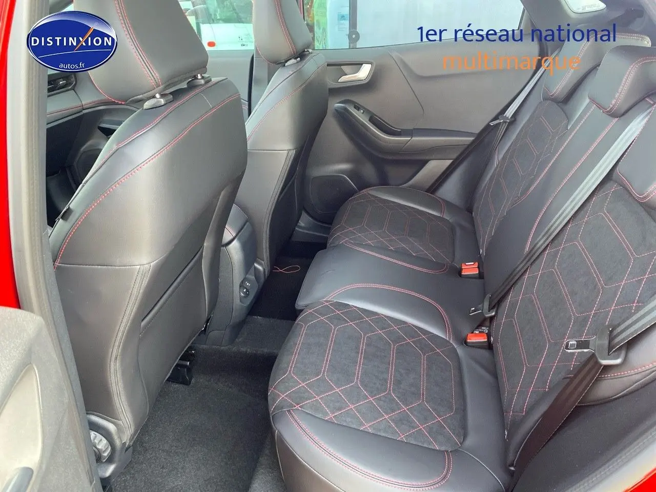 Vue intérieure arrière côté gauche du Ford Puma rouge, sièges en tissu noir avec surpiqûres rouges et détails cuir.