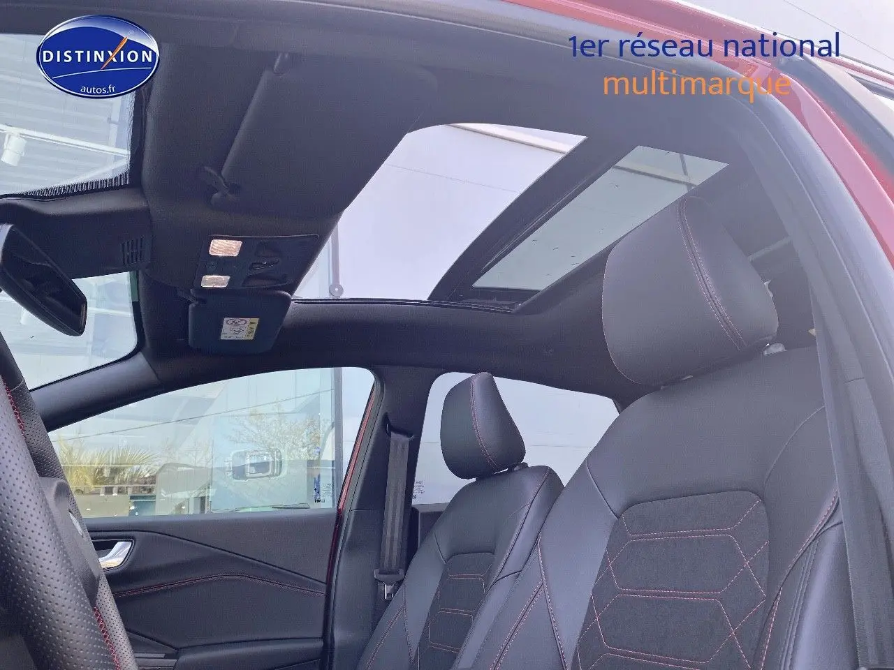 Vue intérieure côté conducteur du Ford Puma rouge avec toit ouvrant panoramique et sièges sport noirs à surpiqûres rouges.