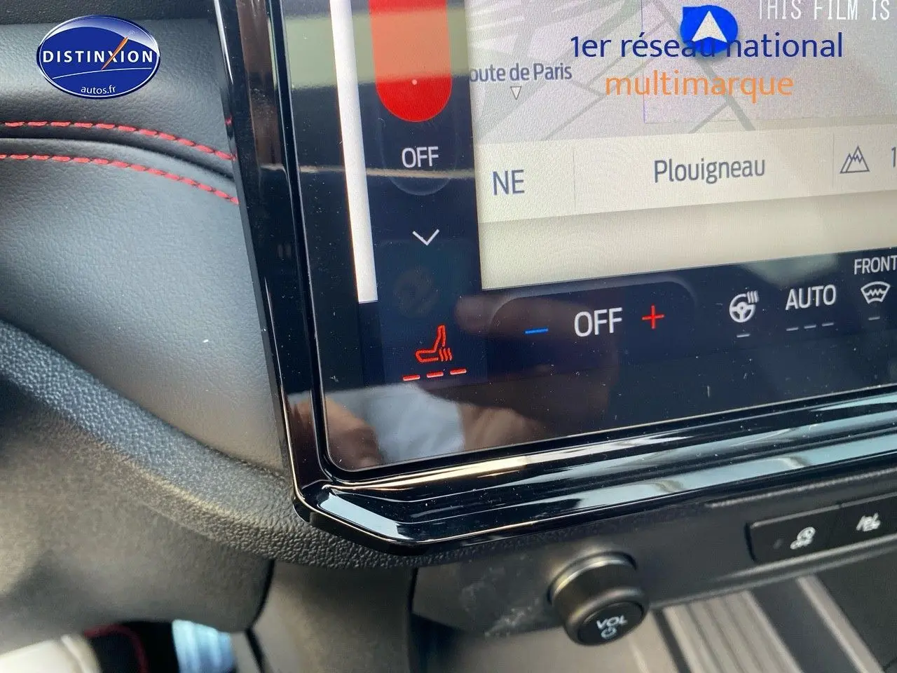 Détail de l’écran tactile central du Ford Puma rouge avec commandes de climatisation et sièges chauffants, intérieur noir avec surpiqûres rouges.