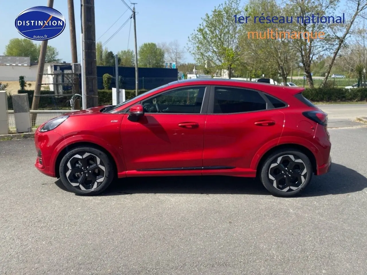 Vue de profil côté gauche d'un Ford Puma rouge métallisé avec jantes alliage noires et toit ouvrant panoramique.