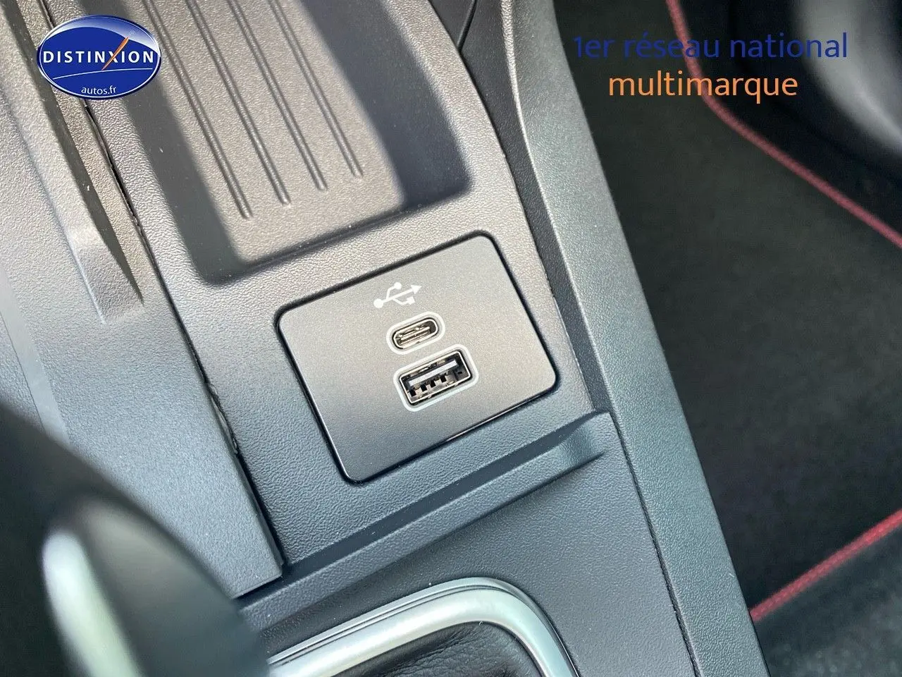Vue rapprochée du port USB-C et USB-A sur la console centrale du Ford Puma rouge, avec surpiqûres rouges visibles.